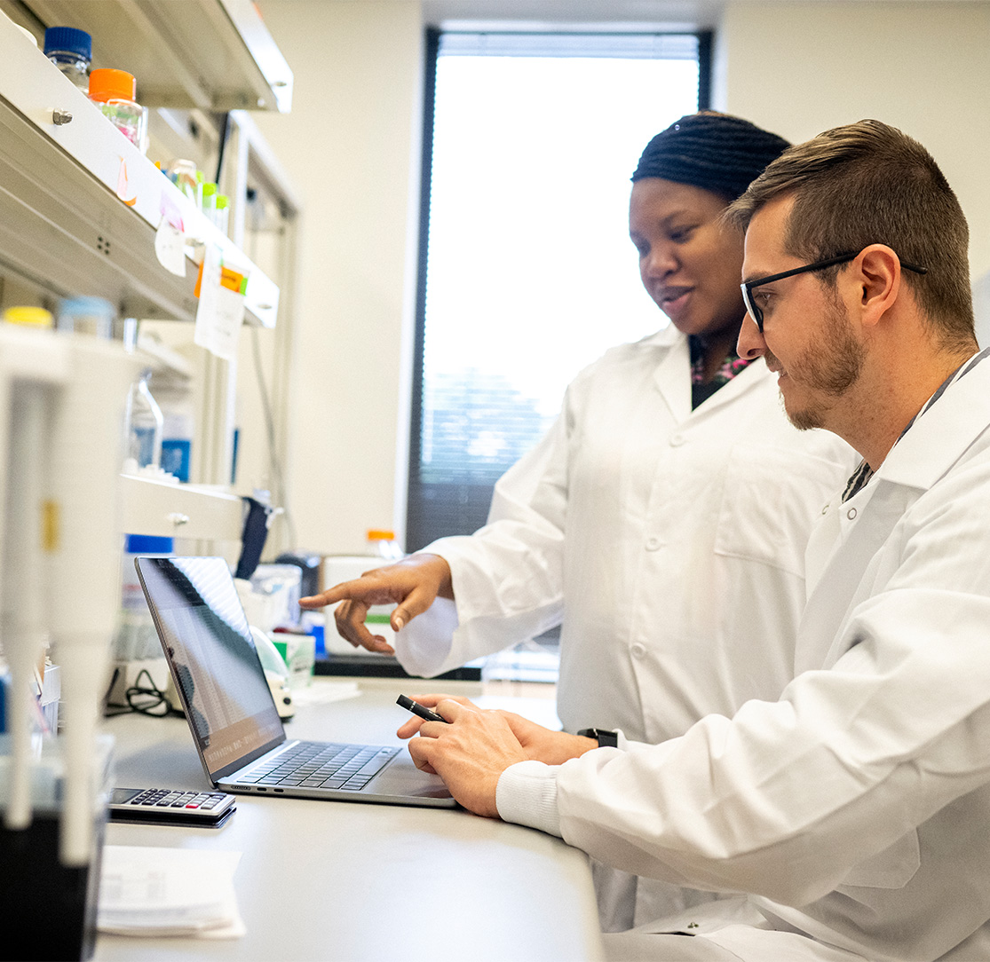 Two lab workers looking at a computer