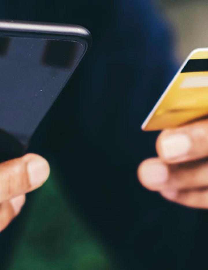 Two hands holding a credit card and a cell phone