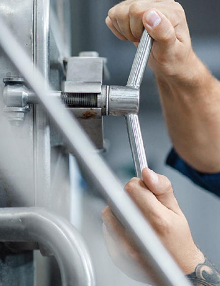 A man working in a brewery is turning a handle