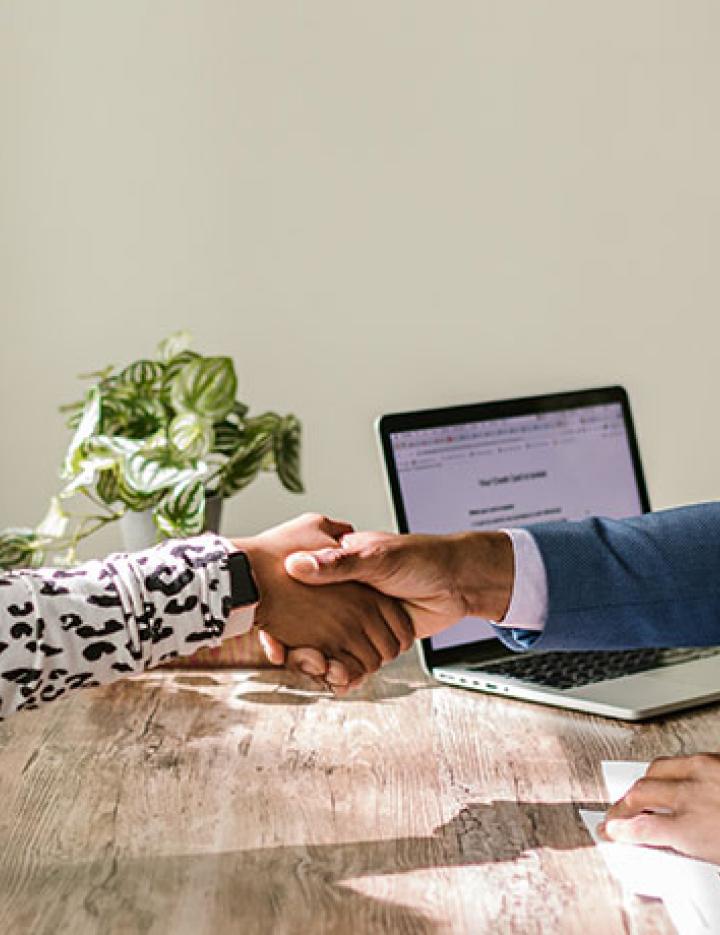 Three people discuss business and numbers at a table.