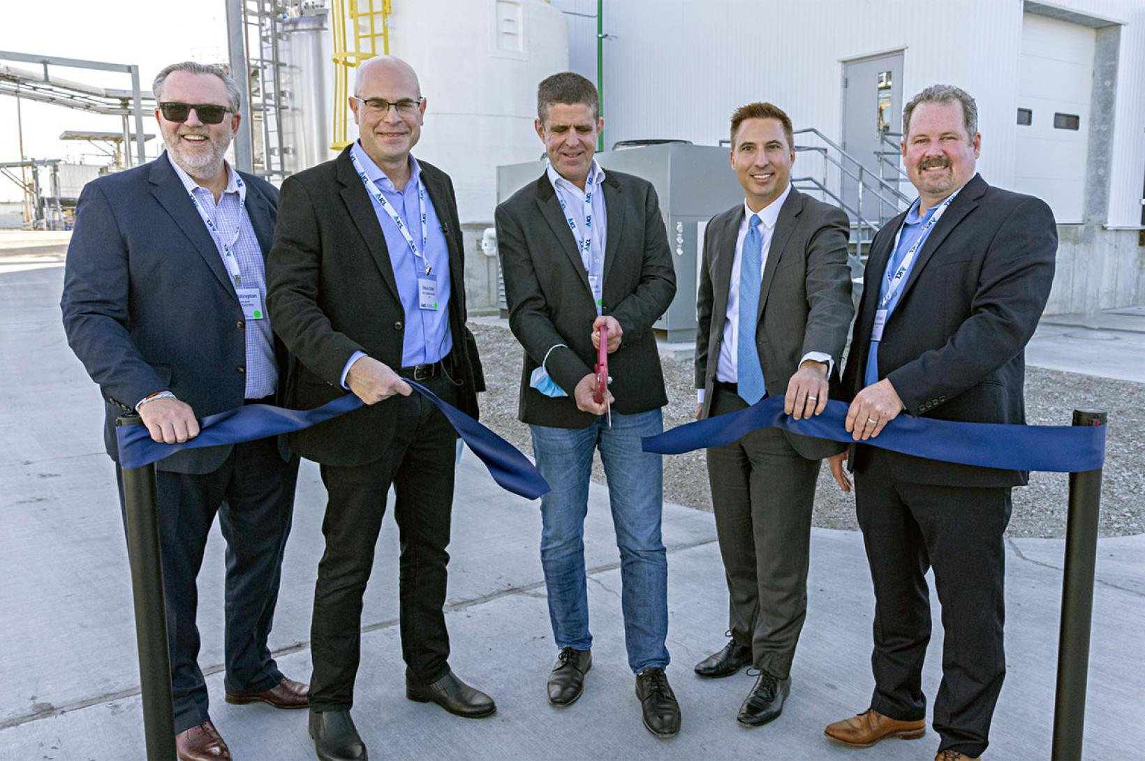 A group of business men cut a ribbon