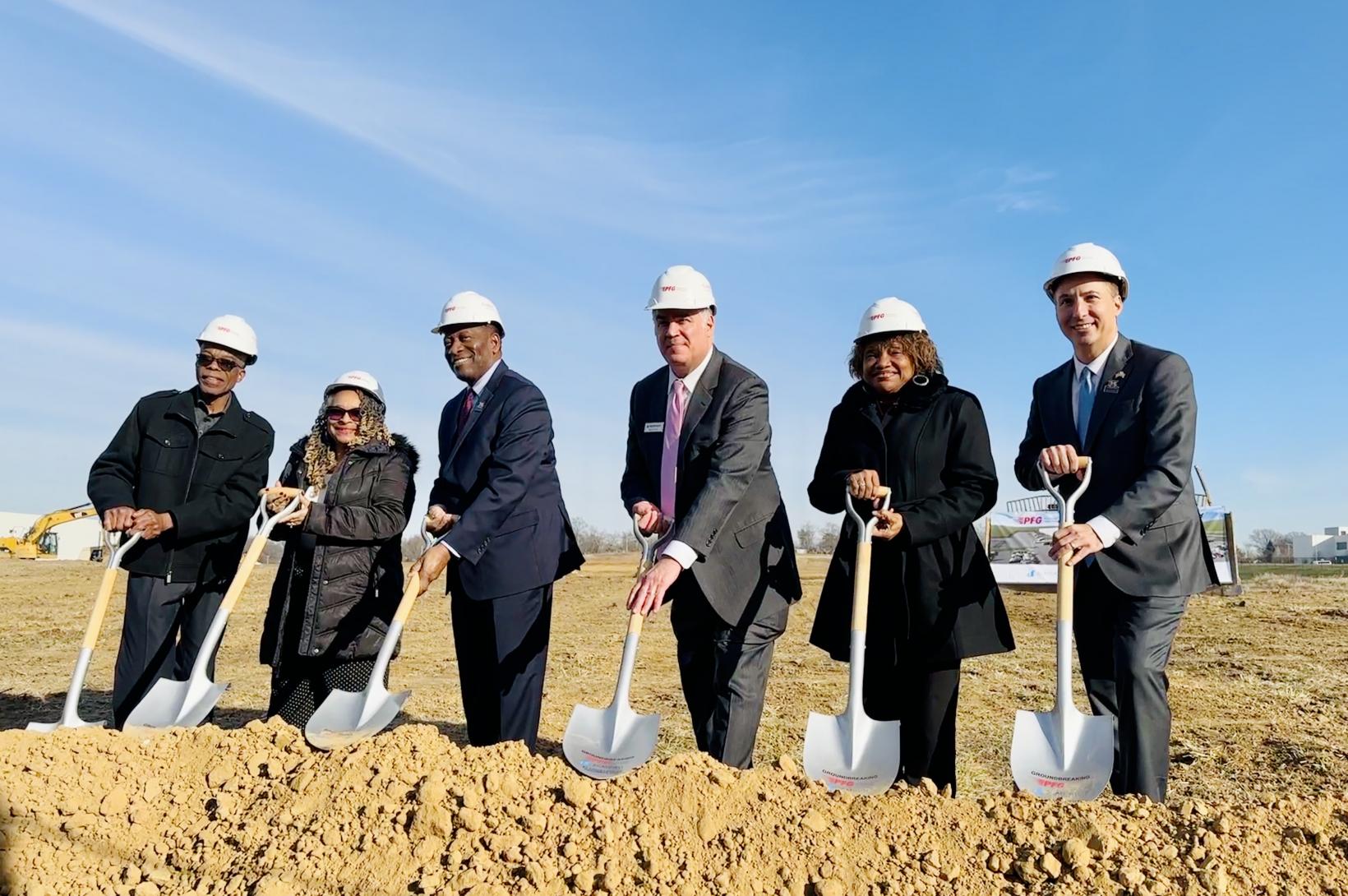 Six business and civic leaders stand with shovels and hard hats at the new PFG facility in North St. Louis County.
