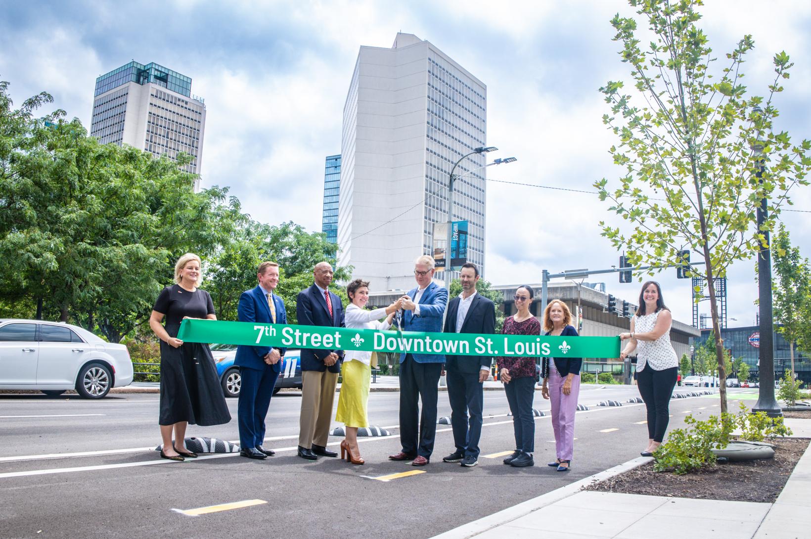 A group of St. Louis leaders cuts a green ribbon, celebrating the redevelopment of 7th Street in Downtown.