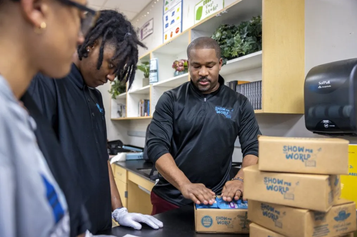Sylvester Chisom works with students boxing up Show Me the World coffee orders.